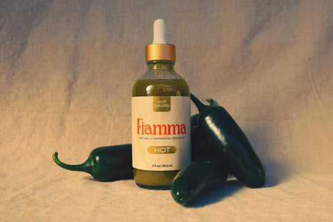 Fiamma hot sauce bottle with peppers on a textured beige background